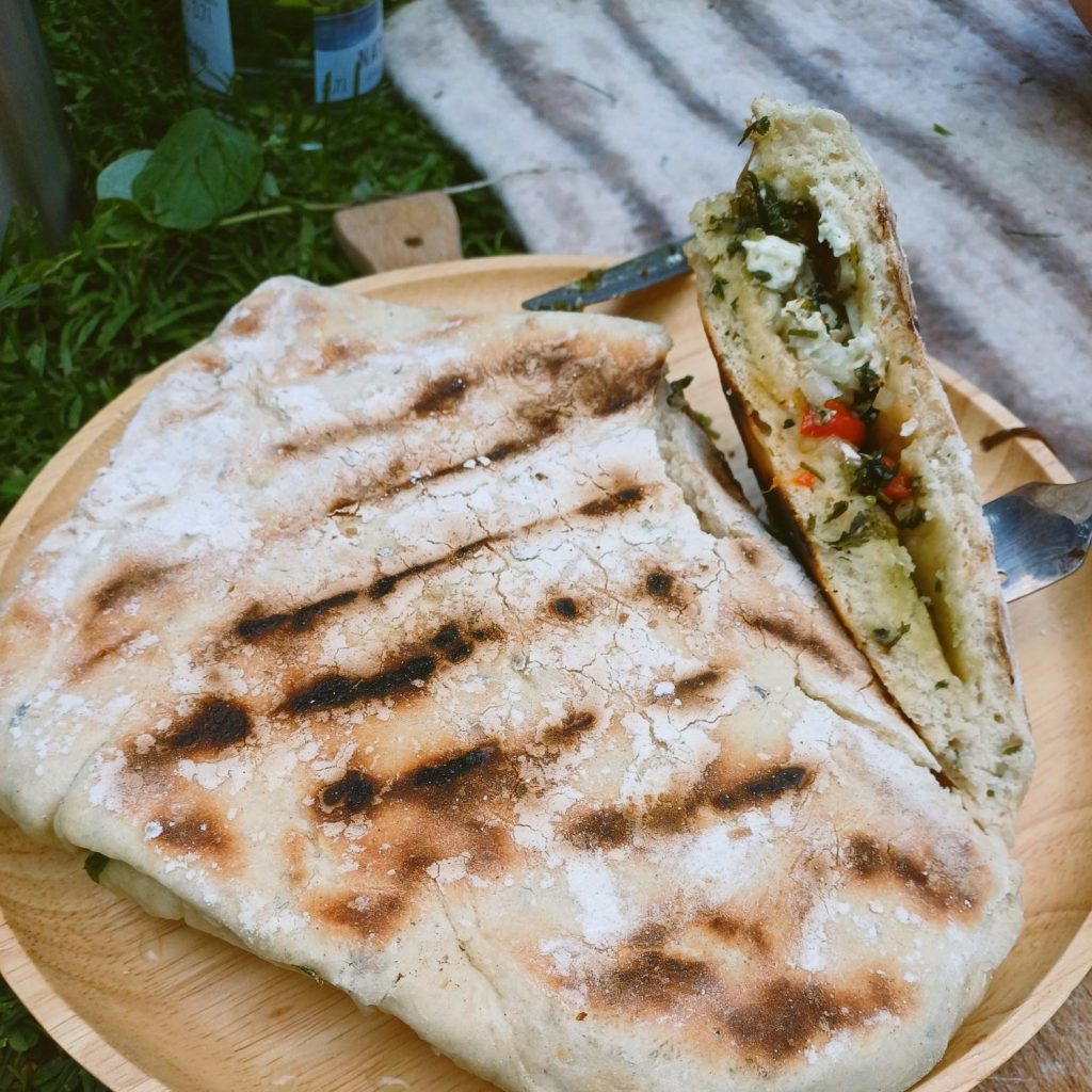 Auf dem Feuer gebackene Calzone mit Wildkräutern bei einem Outdoor-Kochseminar
