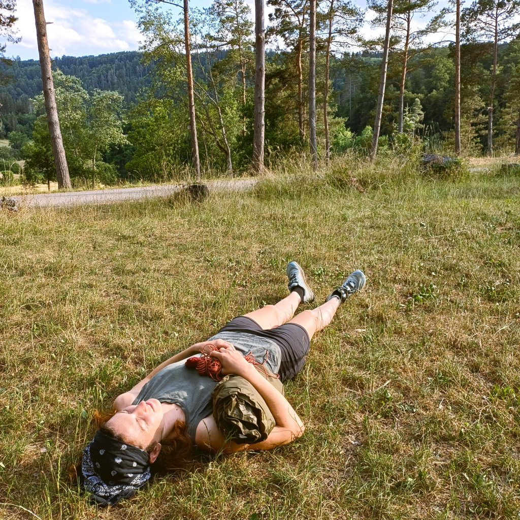 Pause bei einer geführten Trekkingtour: Eine Frau ruht sich auf einer Wiese aus